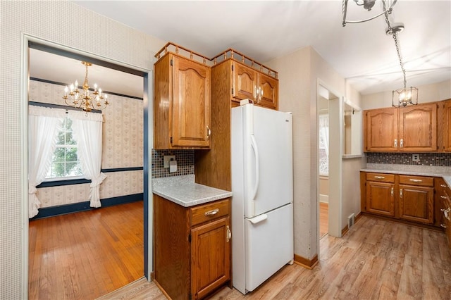 kitchen featuring white refrigerator, light hardwood / wood-style flooring, an inviting chandelier, and decorative light fixtures