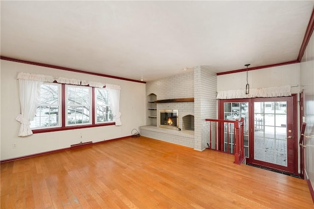 unfurnished living room with a brick fireplace, hardwood / wood-style flooring, and ornamental molding