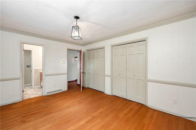 unfurnished bedroom featuring multiple closets, ornamental molding, light hardwood / wood-style floors, and a baseboard radiator