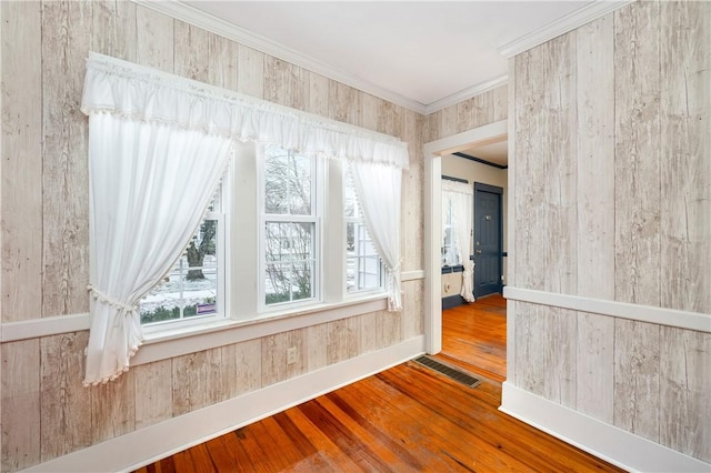 spare room with ornamental molding, a healthy amount of sunlight, and hardwood / wood-style floors