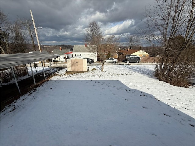 yard covered in snow featuring a carport and a shed