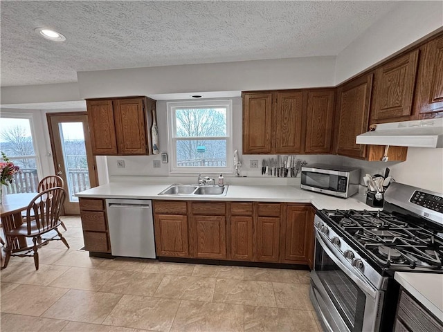 kitchen featuring stainless steel appliances, sink, a textured ceiling, and a wealth of natural light