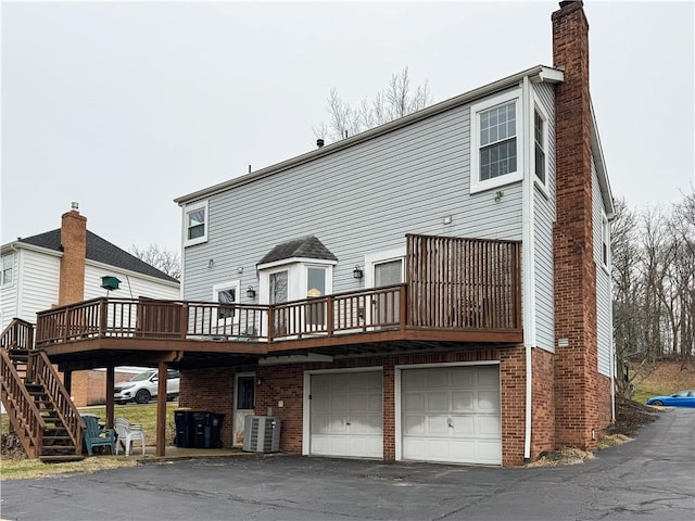 rear view of property with a wooden deck, a garage, and cooling unit