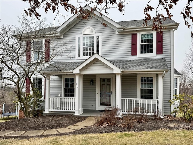 view of front facade with a porch, a trampoline, and a shingled roof