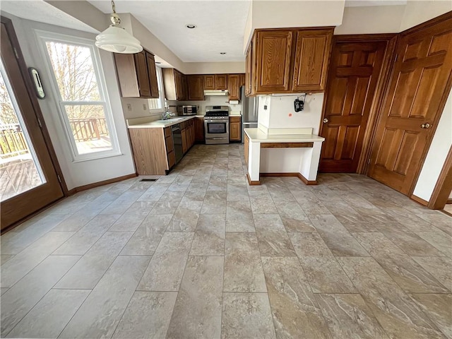 kitchen featuring under cabinet range hood, light countertops, stainless steel appliances, brown cabinets, and baseboards