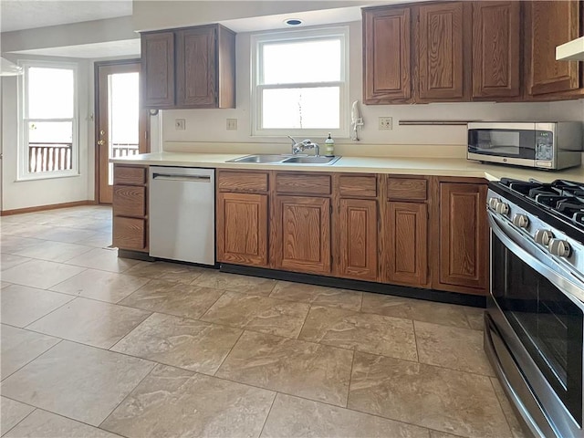 kitchen with light countertops, a sink, baseboards, and stainless steel appliances