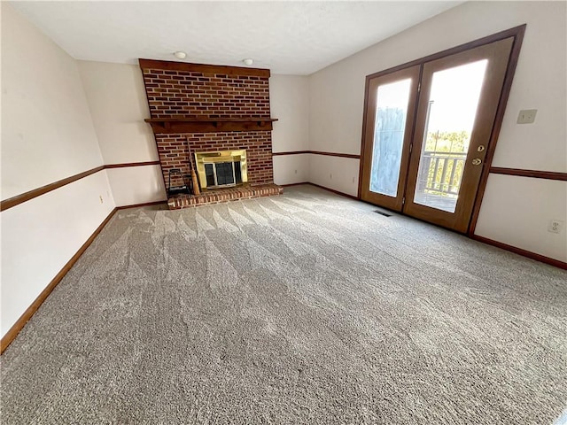 unfurnished living room featuring a brick fireplace, visible vents, baseboards, and carpet
