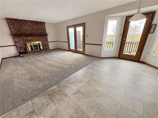 unfurnished living room featuring a fireplace, baseboards, and a wealth of natural light