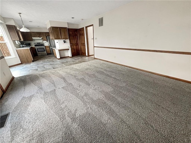 interior space featuring visible vents, light carpet, light countertops, open floor plan, and baseboards