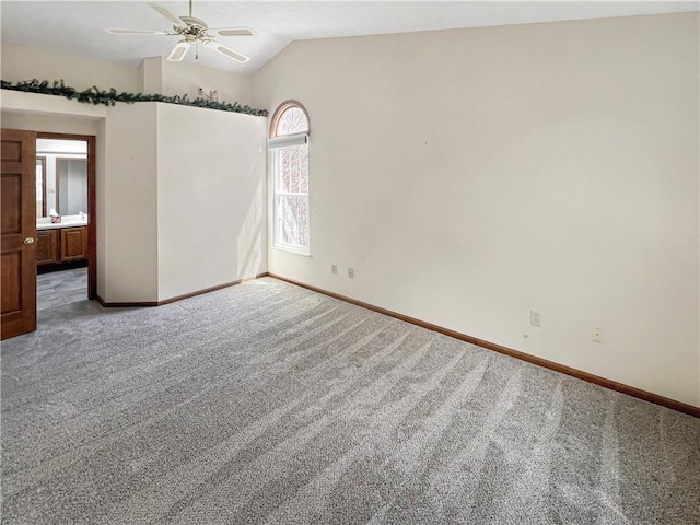 unfurnished bedroom featuring carpet flooring, baseboards, ensuite bath, and lofted ceiling