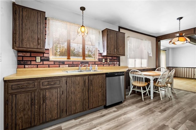 kitchen featuring stainless steel dishwasher, sink, light hardwood / wood-style floors, and hanging light fixtures