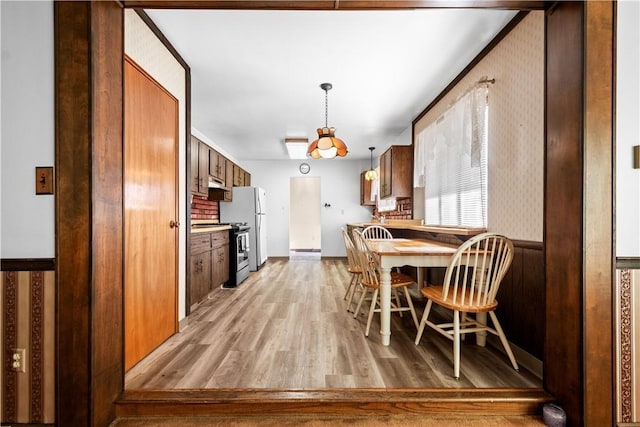 kitchen featuring decorative light fixtures, stainless steel gas range, and light wood-type flooring