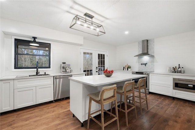 kitchen featuring wall chimney range hood, sink, stainless steel appliances, white cabinets, and french doors