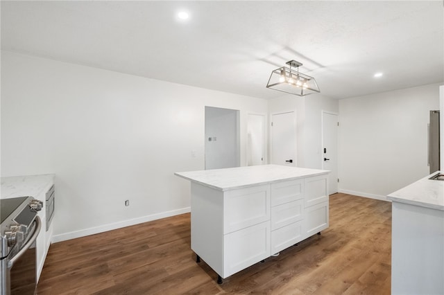 kitchen with stainless steel electric range, a center island, white cabinets, and hardwood / wood-style flooring