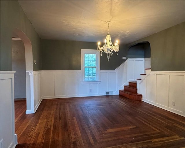 unfurnished dining area featuring dark parquet flooring and a chandelier