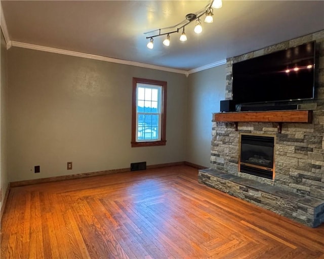 unfurnished living room with crown molding, a stone fireplace, and parquet flooring