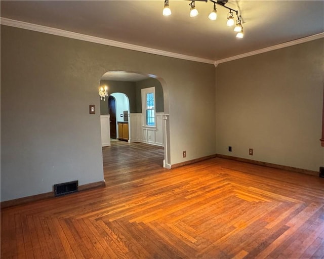 empty room with parquet flooring, ornamental molding, and track lighting