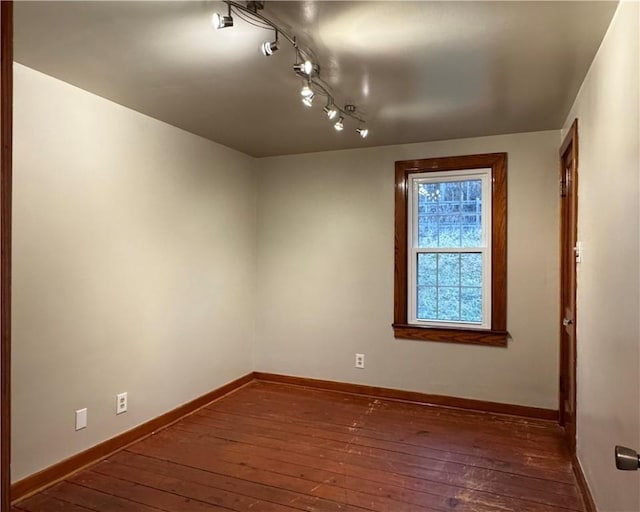 empty room featuring dark hardwood / wood-style flooring and rail lighting