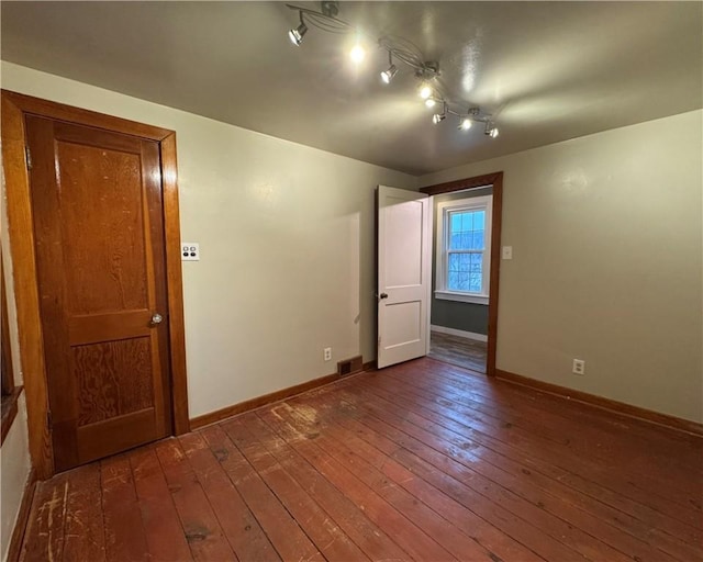 unfurnished room featuring track lighting and dark hardwood / wood-style flooring