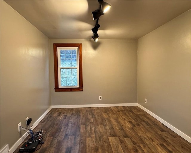 empty room featuring dark hardwood / wood-style flooring and rail lighting