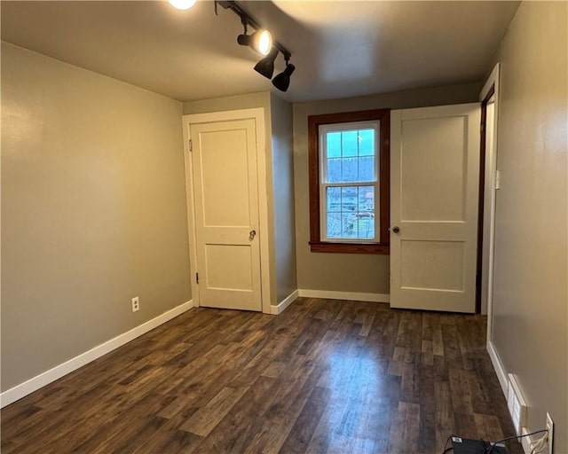 interior space with dark hardwood / wood-style floors and rail lighting