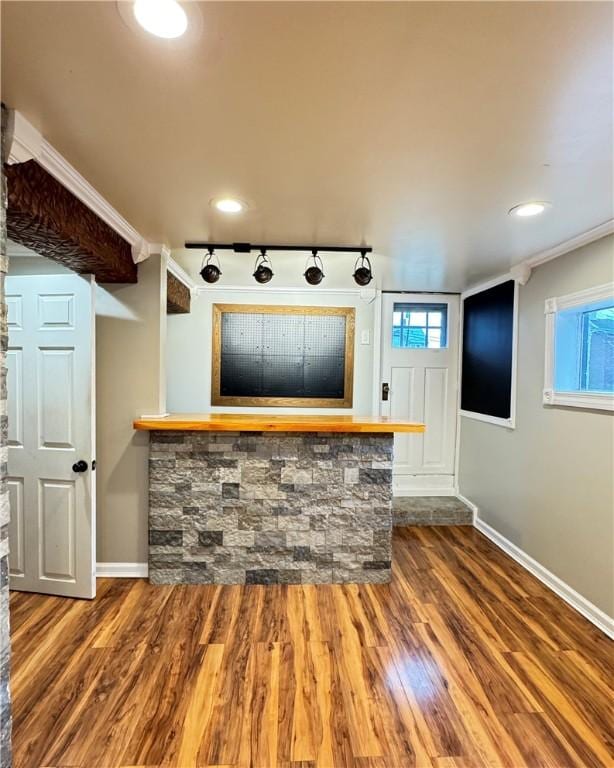 bar featuring ornamental molding, dark wood-type flooring, and track lighting