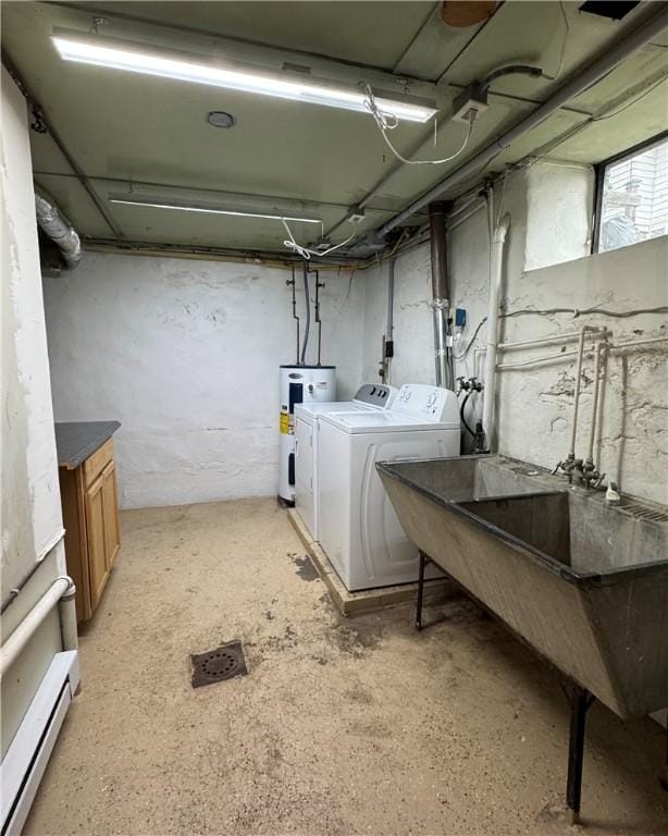 basement featuring a baseboard heating unit, washing machine and dryer, electric water heater, and sink