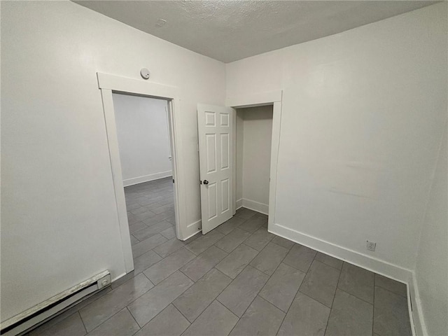 unfurnished room featuring a textured ceiling and a baseboard heating unit