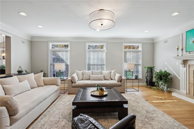 living room featuring crown molding, a high end fireplace, and light wood-type flooring