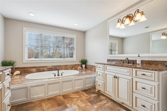 bathroom with a healthy amount of sunlight, a bathing tub, and vanity