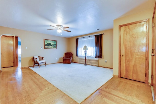 living area featuring light parquet flooring, radiator heating unit, and ceiling fan