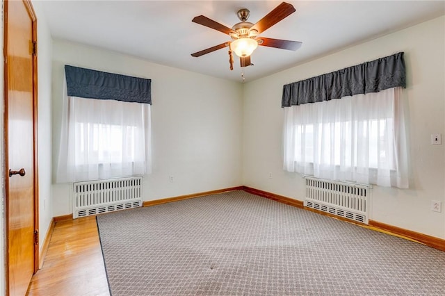 unfurnished room with radiator, a wealth of natural light, and ceiling fan