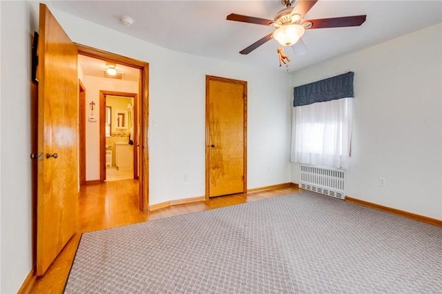 unfurnished bedroom featuring ceiling fan, radiator heating unit, and light wood-type flooring