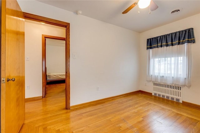 empty room with hardwood / wood-style floors, radiator heating unit, and ceiling fan