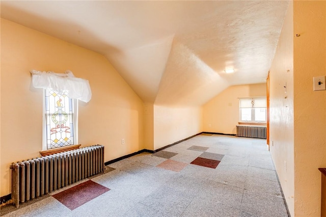 bonus room with vaulted ceiling, radiator heating unit, and a textured ceiling