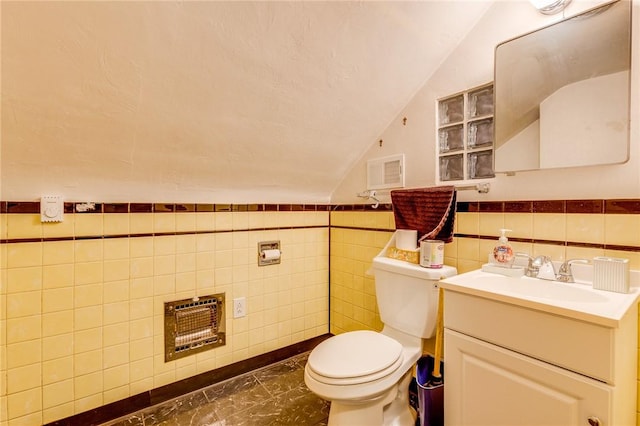 bathroom with lofted ceiling, tile walls, heating unit, vanity, and toilet