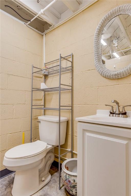 bathroom with vanity, toilet, and concrete floors