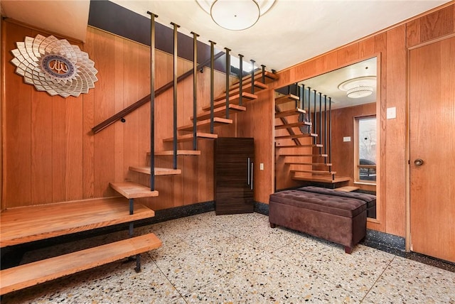 stairway featuring wooden walls