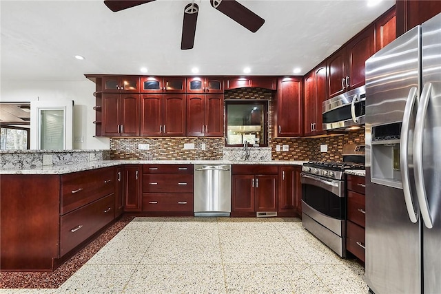 kitchen with appliances with stainless steel finishes, sink, decorative backsplash, light stone counters, and ceiling fan