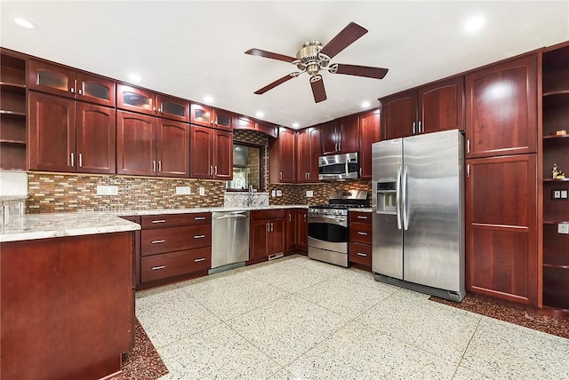kitchen with appliances with stainless steel finishes, sink, decorative backsplash, ceiling fan, and light stone countertops