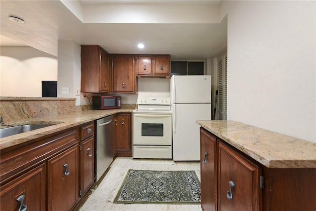 kitchen featuring white appliances, light stone countertops, and kitchen peninsula