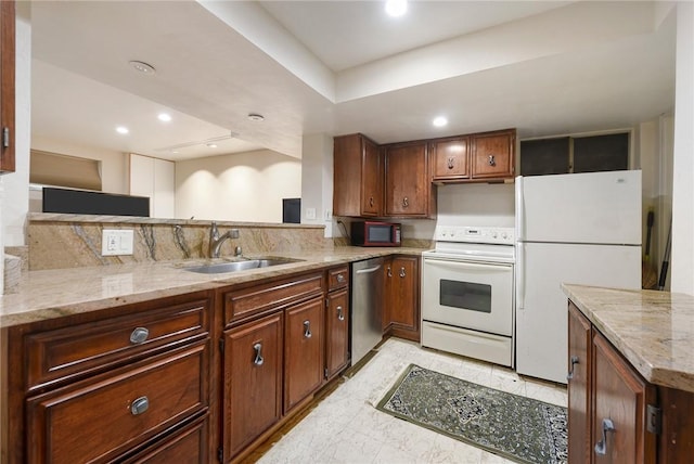 kitchen with light stone counters, sink, white appliances, and kitchen peninsula