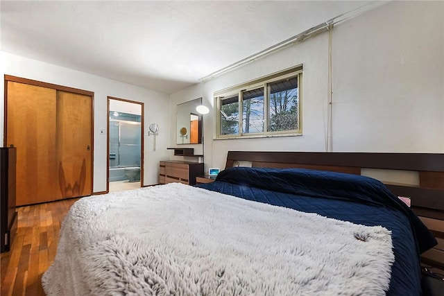 bedroom with hardwood / wood-style floors and ensuite bathroom