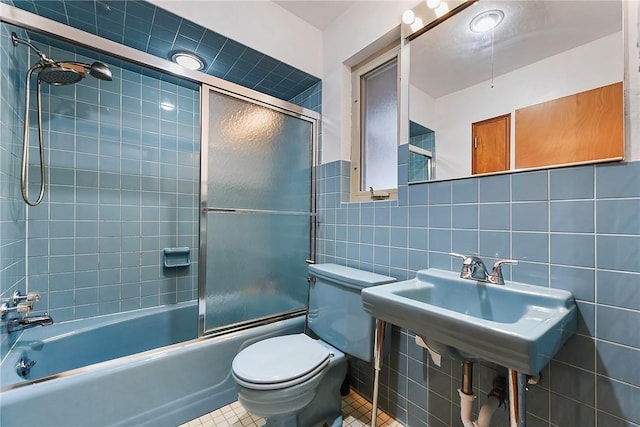 full bathroom featuring sink, combined bath / shower with glass door, tile walls, tile patterned floors, and toilet