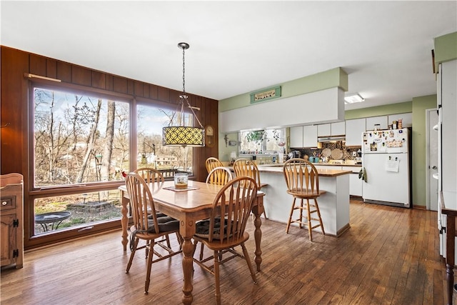 dining area featuring wooden walls and dark hardwood / wood-style flooring