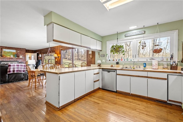 kitchen featuring sink, dishwasher, kitchen peninsula, and white cabinets