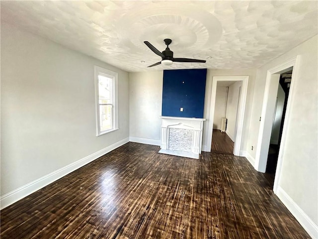 unfurnished living room featuring ceiling fan and dark hardwood / wood-style flooring