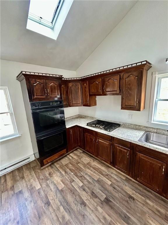 kitchen featuring dark brown cabinetry, sink, stainless steel gas cooktop, black double oven, and hardwood / wood-style floors