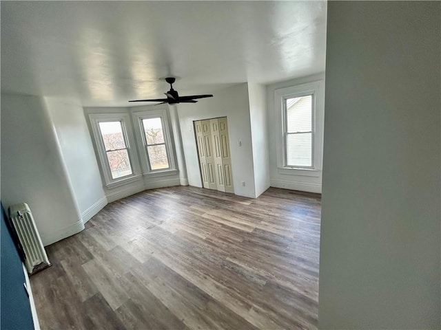 empty room featuring wood-type flooring, radiator, and ceiling fan