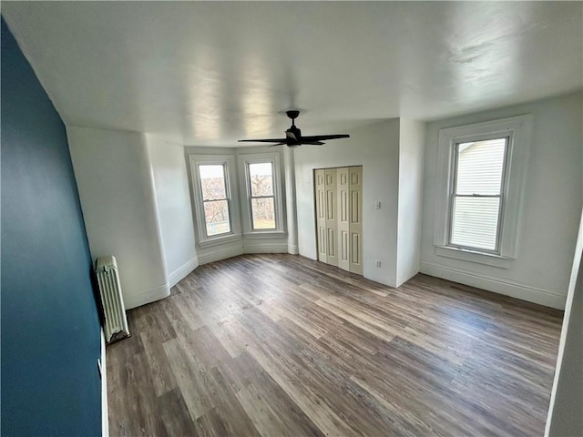 unfurnished bedroom featuring radiator heating unit, ceiling fan, and light wood-type flooring